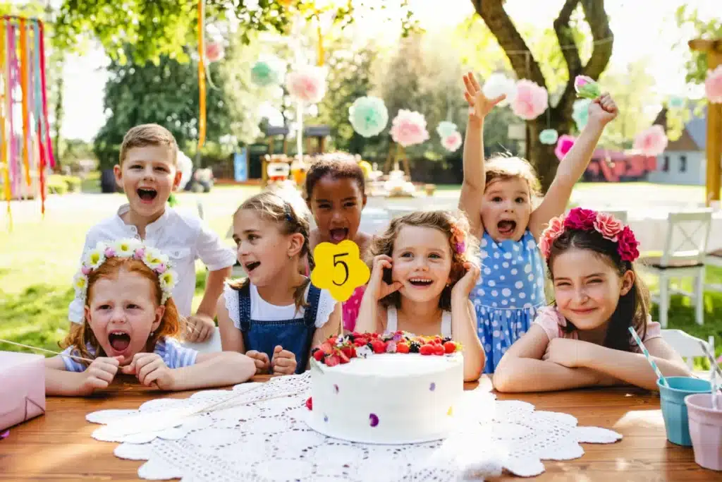 Children playing fun birthday party games together at a colorful outdoor kids birthday celebration.
